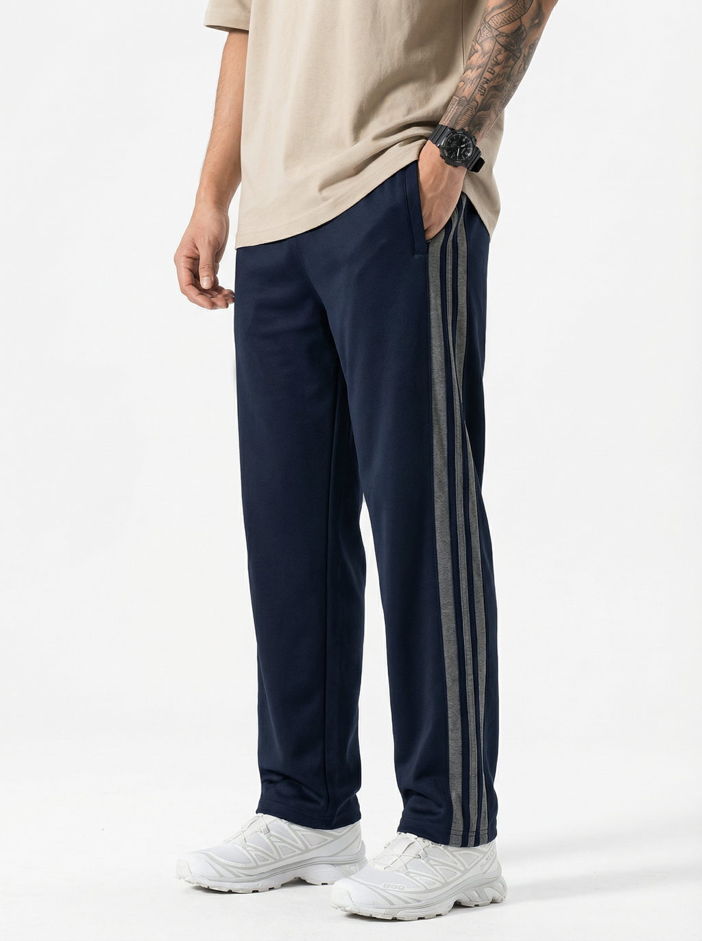Person wearing navy track pants with three stripes on a white background